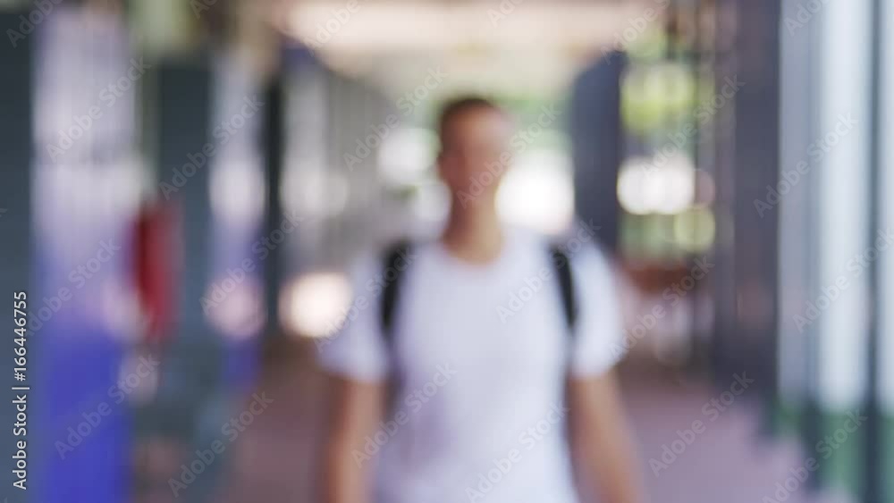 Mixed race teenage boy walks into focus in school corridor Mixed race teenage boy walks into focus in school corridor