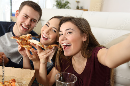 Friends taking selfies and eating pizza