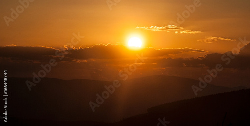 sunset in mountains with hills, colorful sky, sun eith sunlights and clouds © honza28683