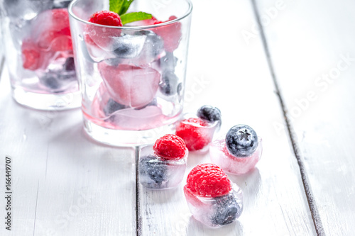 Frozen berries in glass for cocktail on wooden table background