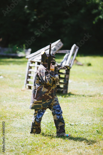Paintball sport player in uniform and mask with gun outdoors