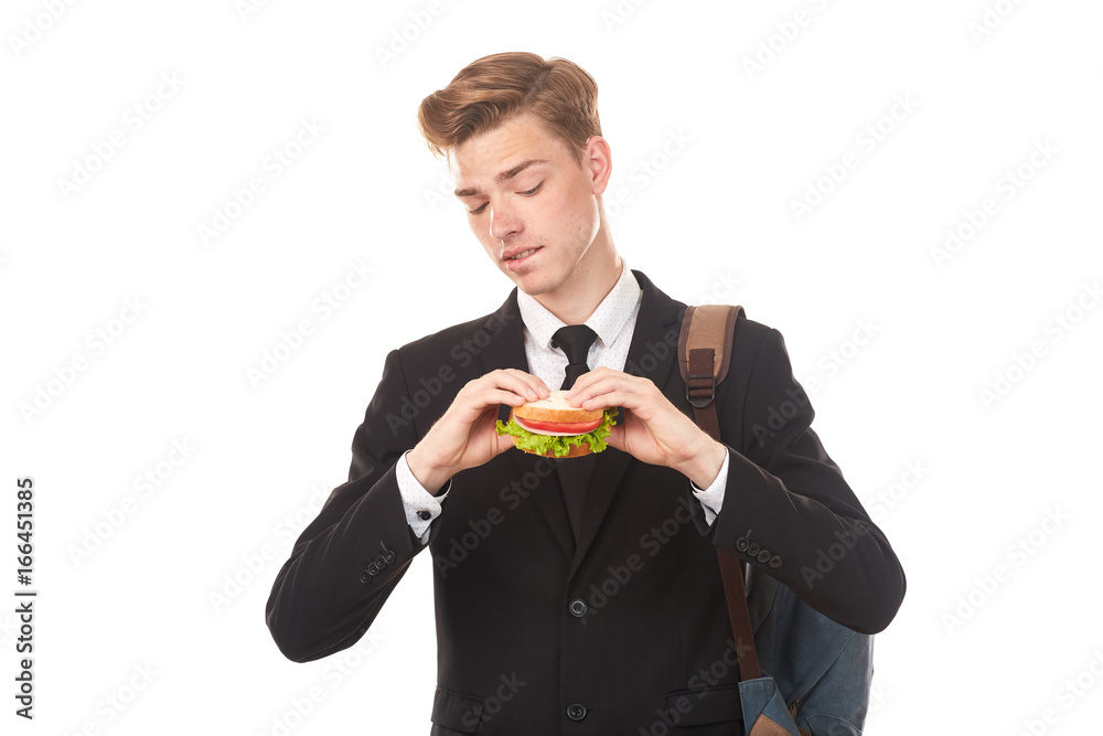 Portrait of college student in black suit eating sandwich against white background Portrait of college student in black suit eating sandwich against white background