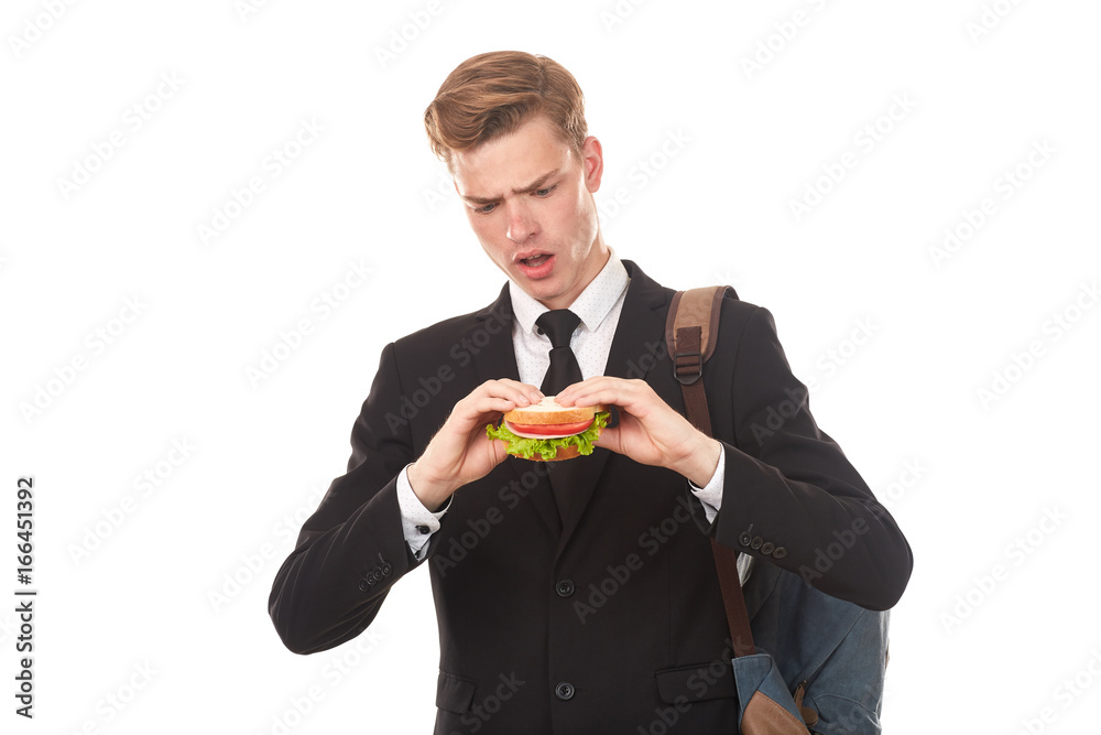 Portrait of college student in black suit eating sandwich against white background Portrait of college student in black suit eating sandwich against white background