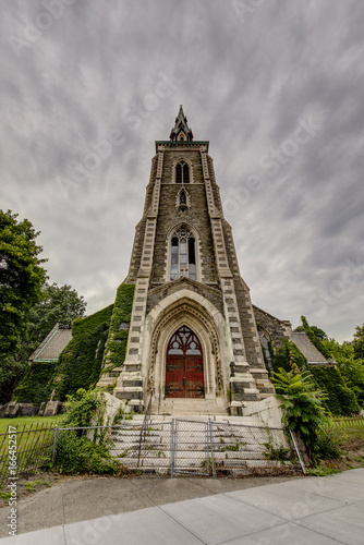 Abandoned & Historic Church with Wrought Iron Fence on Cloudy Morning