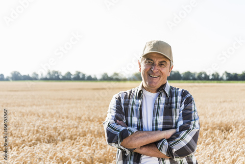 Portrait of laughing senior farmer standing in front of a field