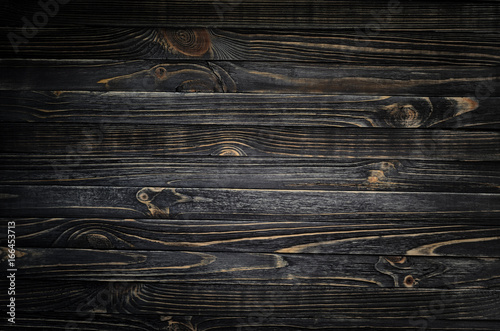Black wood striped texture with vignette. A wooden surface lit by a spot of light