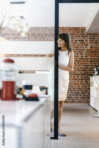 Businesswoman standing in office, looking around corner