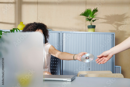 Woman handing over DVD to co-worker photo