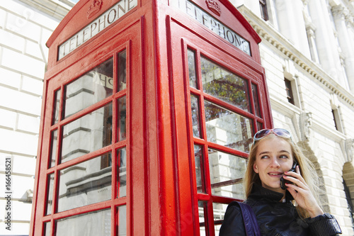 Woman next to phone booth, on her cell photo