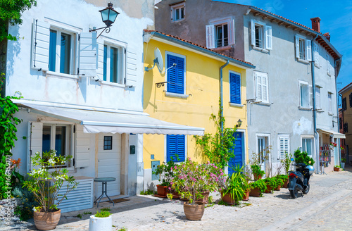 Fototapeta Naklejka Na Ścianę i Meble -  Traditional European Mediterranean architectural style in the streets and residential houses, yard, porches, stairs, shutters in the noon sunbeam, surrounded by vine, rhododendron at summertime.