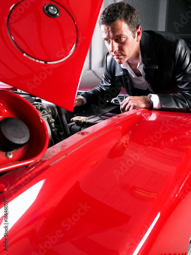 Fotografie Man watching a V12 motor in a Ferrari.