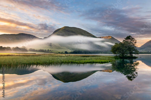 A beautiful summer sunrise with early morning mists rolling through valley in the English Lake District. photo