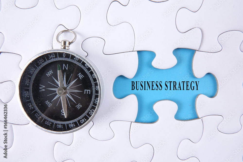 Jigsaw puzzle and compass with BUSINESS STRATEGY words.
