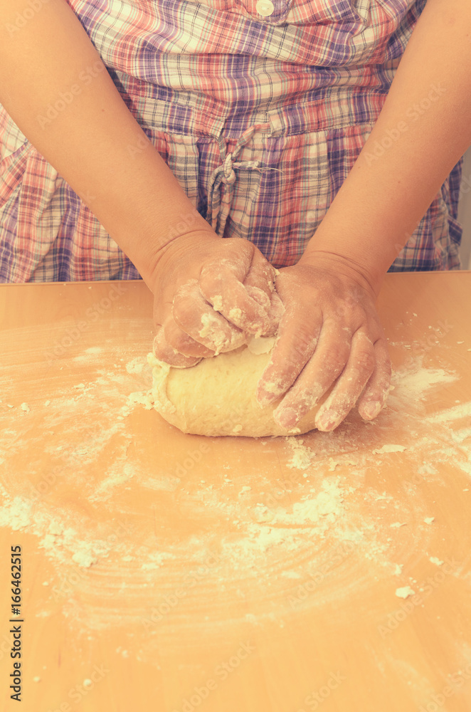 A woman kneads a homemade dough for pizza production.