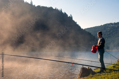 Adult Man fishing early in the morning on mountain lake