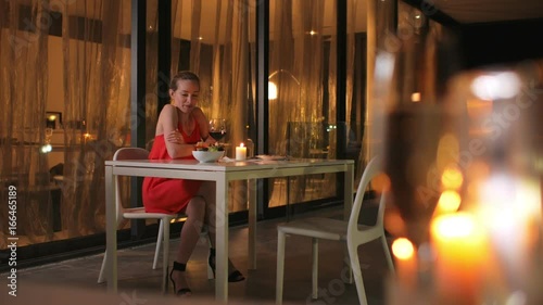 A young girl sits in the evening on the terrace og the restaurant and freezes