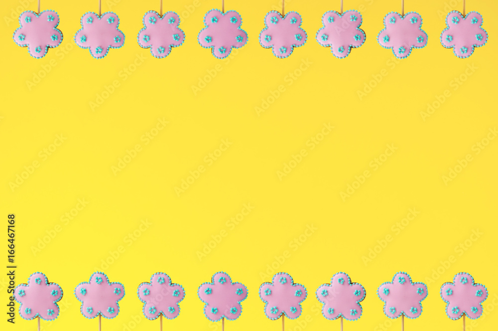 Frame of homemade gingerbreads in the form of pink flowers on the yellow background. Picture for a menu or a confectionery catalog. Invitation or greeting card.