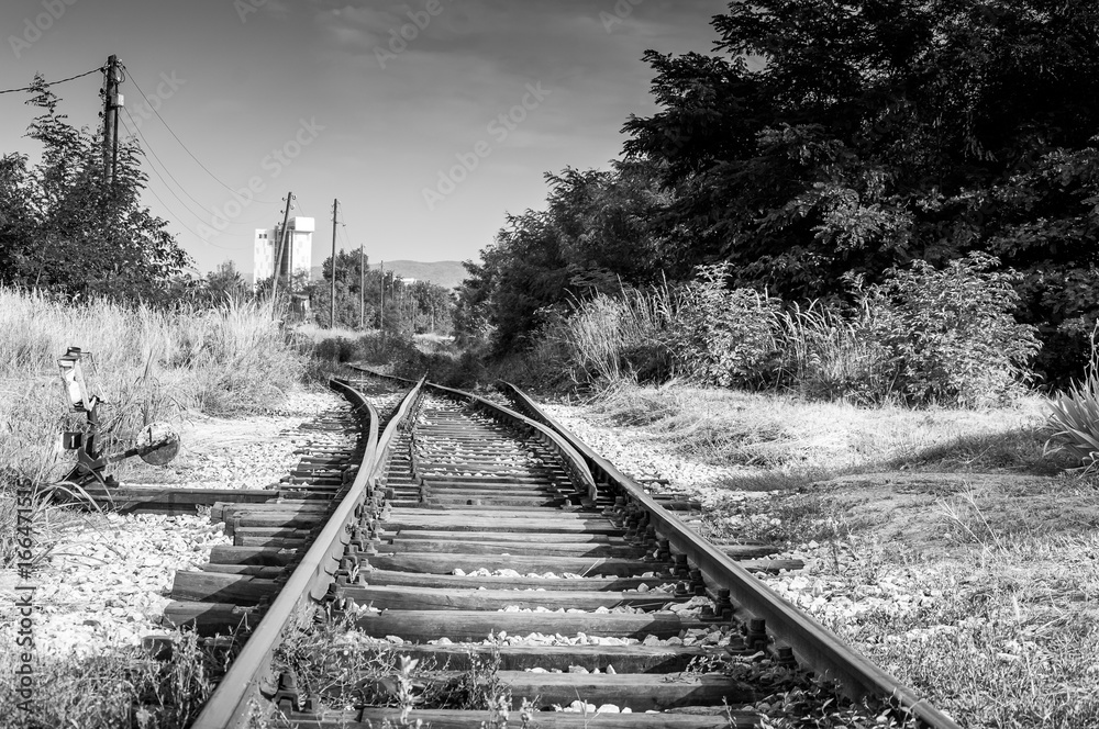 Old abandoned railroad with city in the background. Black and white. Selective focus. Low point of view. Old abandoned railroad with city in the background. Black and white. Selective focus. Low point of view.