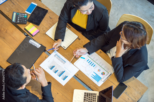 Female employees are explaining sales summary report to top management.
