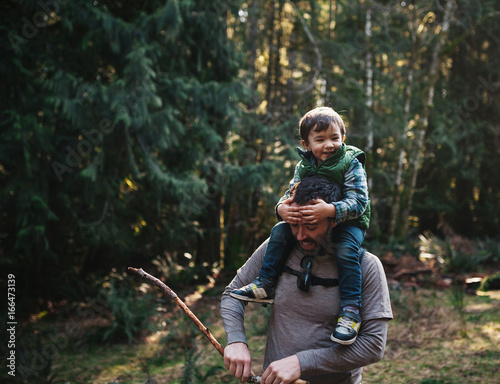 Young dad enjoying hike with happy little boy on his shoulders