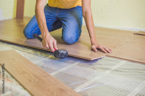 Man installing new wooden laminate flooring. infrared floor heating system under laminate floor photo