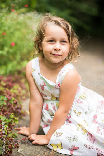 Portrait of a pretty little girl sitting in a garden
