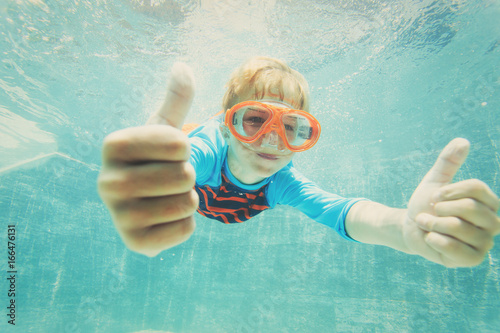 happy boy swimming underwater with thumbs up