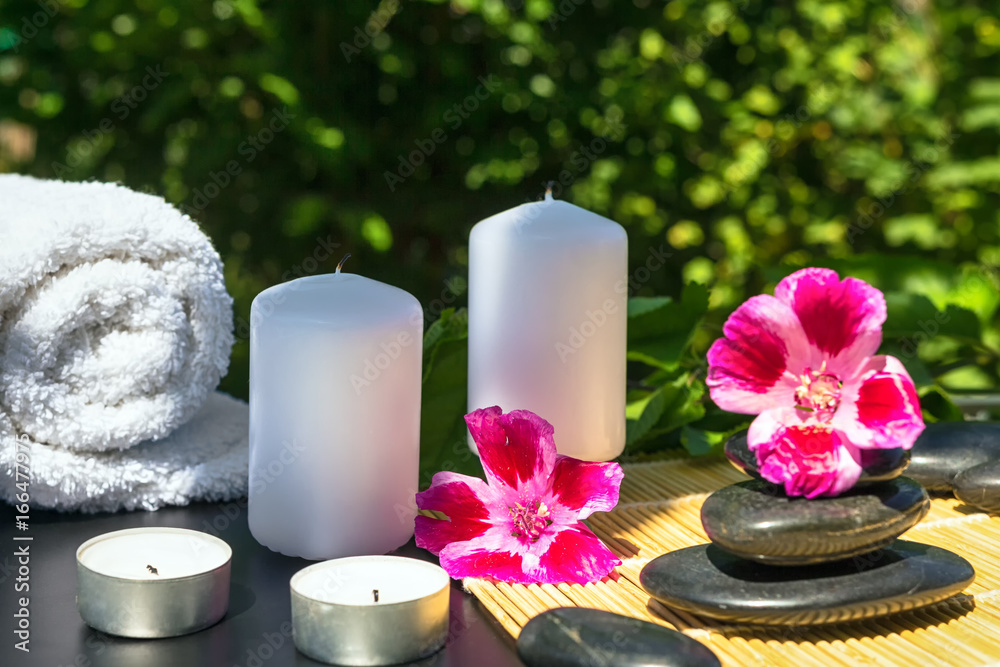 Candles, flowers, stones on a background of greenery for spa massage relaxation Candles, flowers, stones on a background of greenery for spa massage relaxation