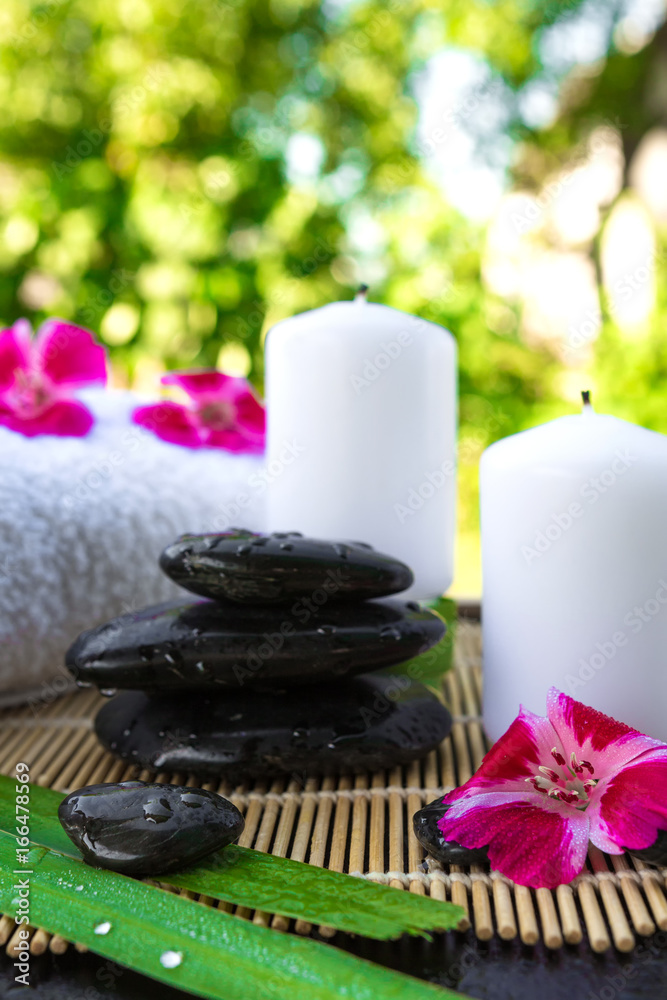 Candles, flowers, stones on a background of greenery for spa massage relaxation Candles, flowers, stones on a background of greenery for spa massage relaxation