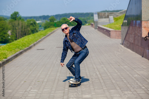 energetic senior man enjoying riding a skateboard. The concept of life satisfaction. Portrait of a positive gray-haired man with a skateboard. winner concept.