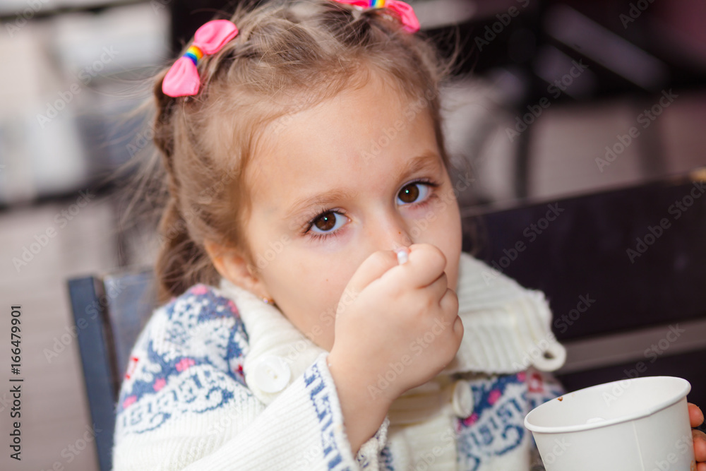 Little girl eating ice cream. Little girl emotionally eating In a cafe on the street Little girl eating ice cream. Little girl emotionally eating In a cafe on the street