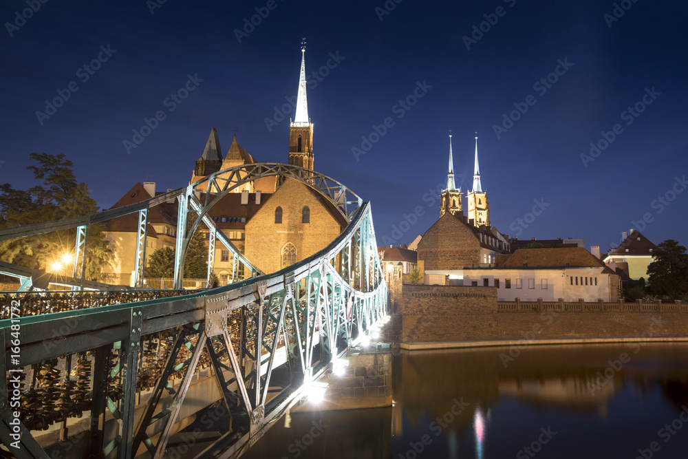 Obraz premium Evening photo of illuminated bridge and St. John the Baptist Cathedral in Wroclaw, Poland