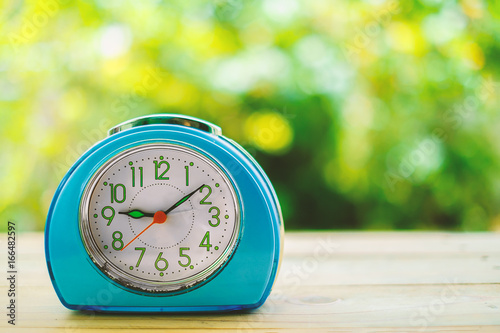 Old blue alarm clock on woo...