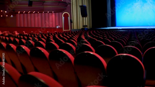 Movement of camera by the seats of an empty theater towards stage 3