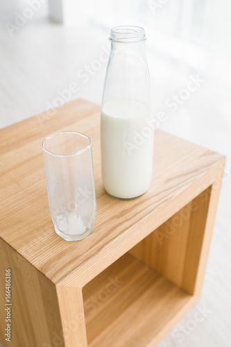 Bottle and glass of milk on wooden table. Natural and rich proteins food, sports and healthcare concept of organic nutrition