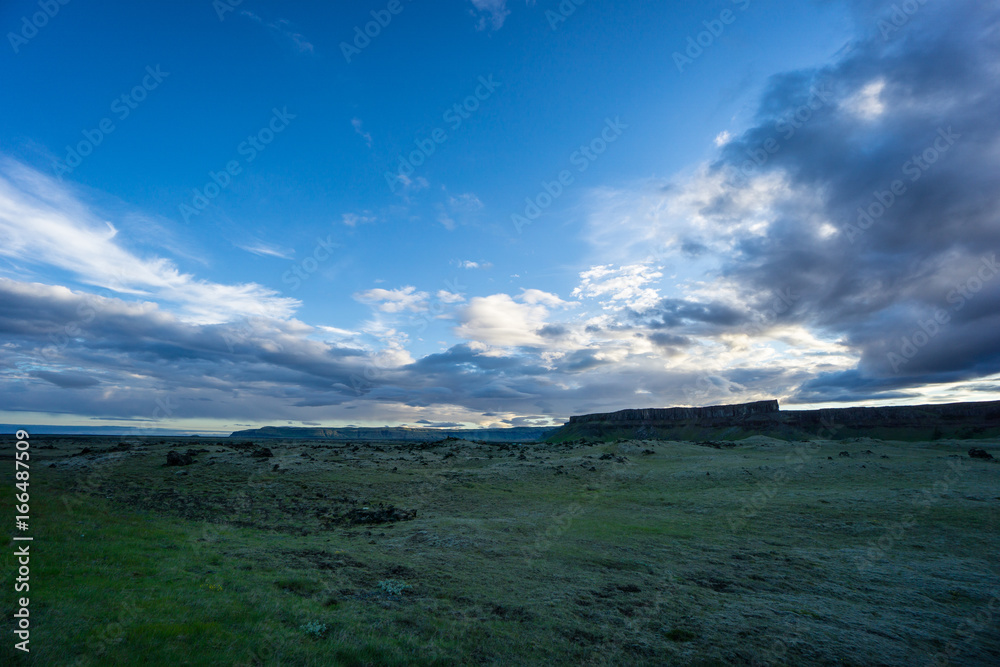 Iceland - Rocky landscape and wide green fields with clouds at dawn