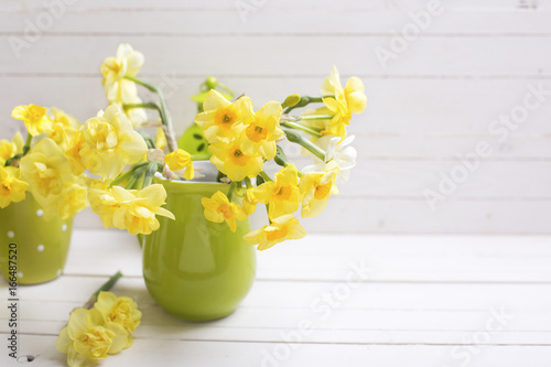 Yellow spring daffodils or narcissus flowers  on white wooden background.