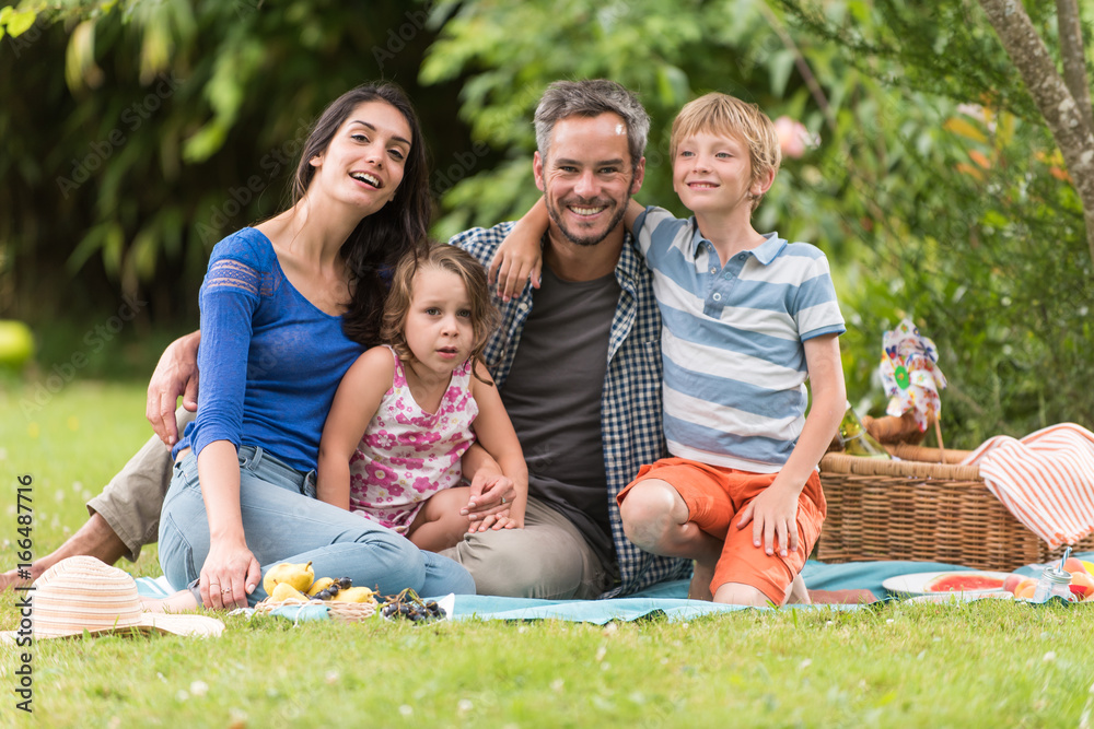 Cheerful family sitting on the grass during un picnic in a park Cheerful family sitting on the grass during un picnic in a park