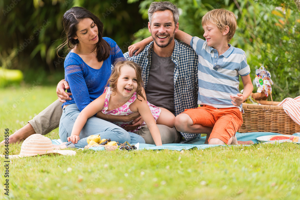 Cheerful family sitting on the grass during un picnic in a park Cheerful family sitting on the grass during un picnic in a park