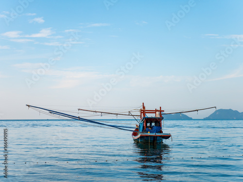 Alone fishing boat with net wooden arms moored in the sea