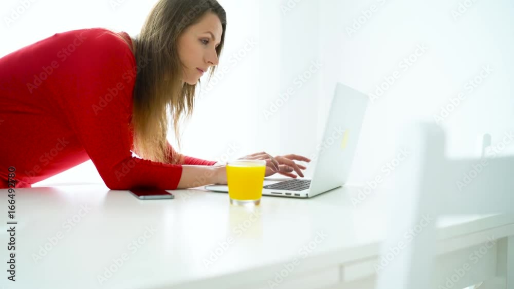 Smiling woman checks email on laptop at white home office Smiling woman checks email on laptop at white home office