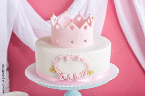 Cute pink cake with a crown on the table to the birthday for a Princess