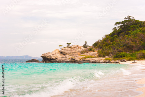 Beautiful tropical beach with clear turquoise water and cliffs, Pattaya, Thailand. Ocean waves on the beach. Copy space for text.
