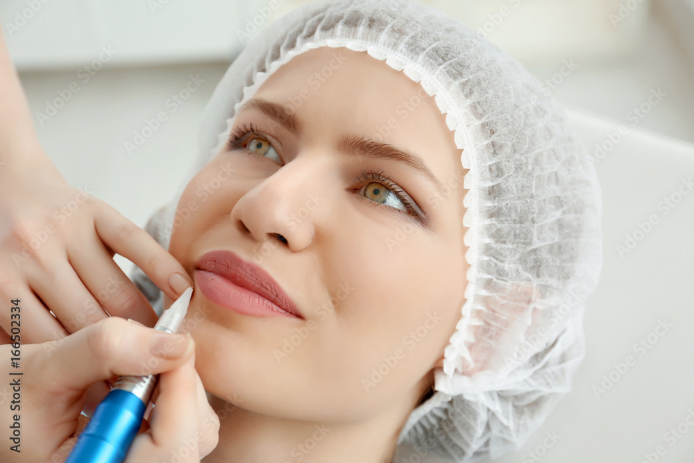 Young woman having permanent makeup on lips in beautician salon Young woman having permanent makeup on lips in beautician salon