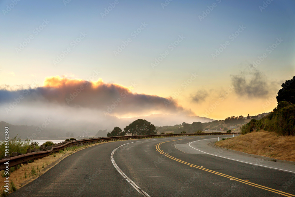 Paved road curve to the right, sunset, cloudy sky