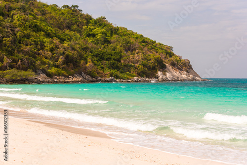 Beautiful tropical beach with clear turquoise water and cliffs, Pattaya, Thailand. Ocean waves on the beach. Copy space.