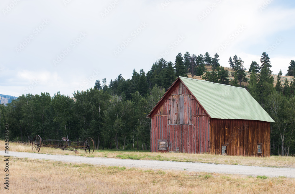 Old red barn near treed ridge, with rustic farm equipment. Old red barn near treed ridge, with rustic farm equipment.