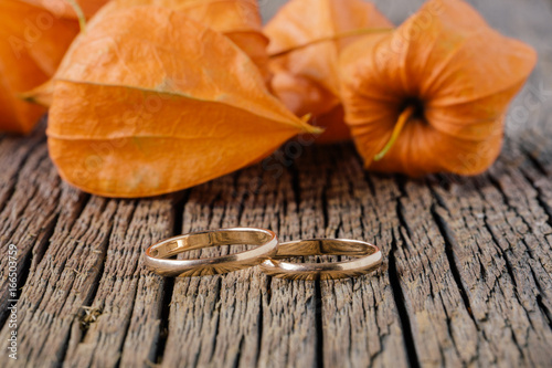 Wedding rings and physalis on background. Concept of autumn wedding