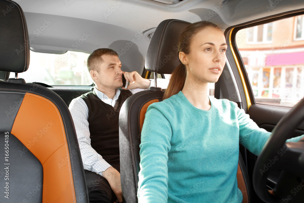Female taxi driver and male passenger talking on phone in car Female taxi driver and male passenger talking on phone in car