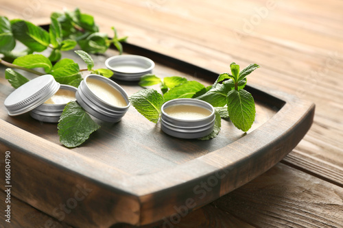 Containers with lemon balm salve and leaves on table photo